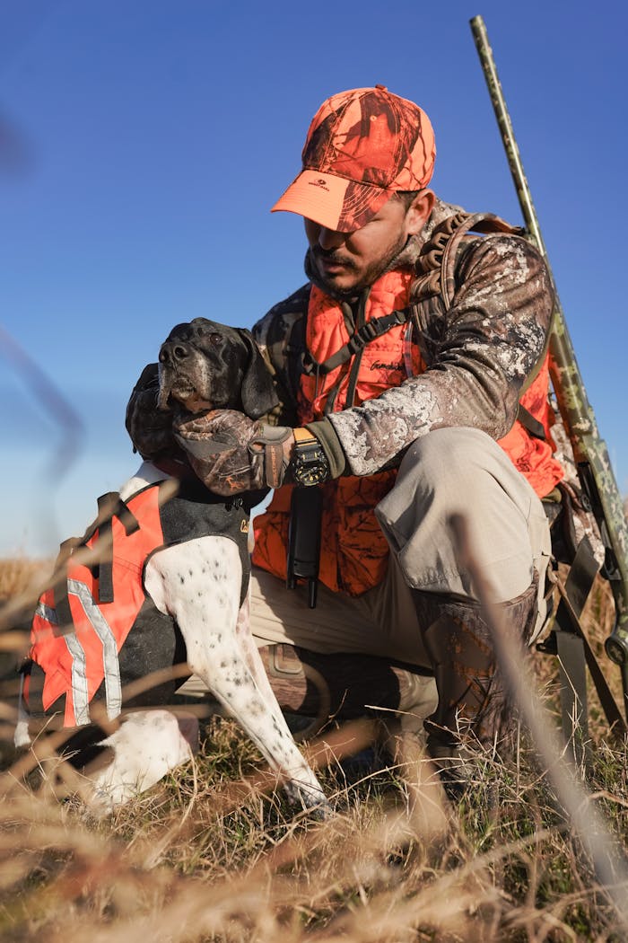 category-05 A hunter kneels beside his dog in a field, showcasing teamwork and outdoor adventure.