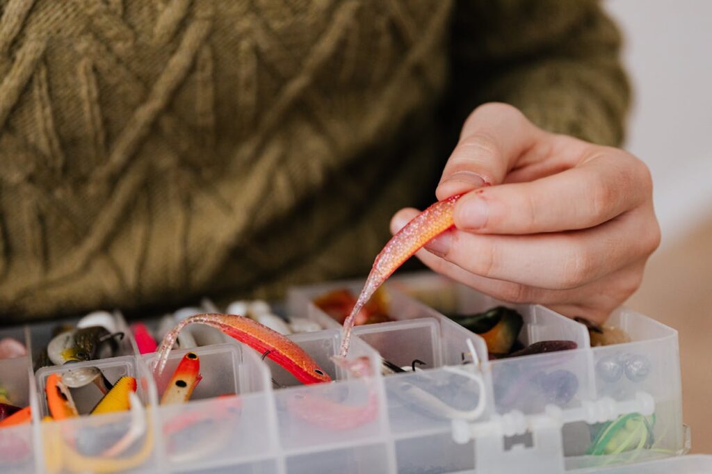 pexels-photo-6478140 Hand selecting vibrant fishing lure from plastic container. Perfect for angling enthusiasts.